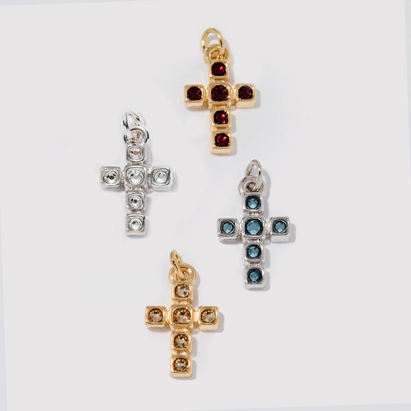 Four cross-shaped pendants in different colors on a white background