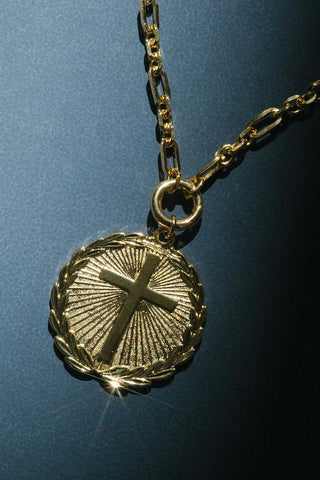 Gold necklace with a cross pendant on a dark blue background