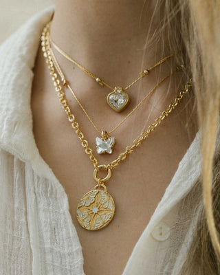 Close-up of a person wearing multiple gold necklaces with heart and starfish pendants.