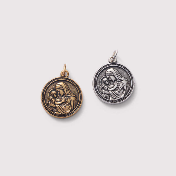 Two religious pendants featuring a mother and child design on a light gray background.