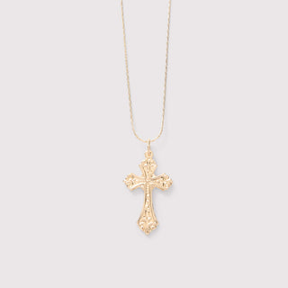 Gold cross necklace on a light gray background