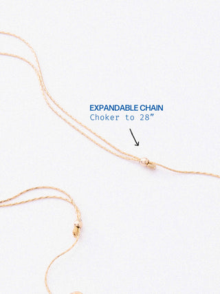 A delicate gold chain necklace with an adjustable expandable knot, shown on a clean white background with blue text reading 'EXPANDABLE CHAIN Choker to 28"' and a black arrow pointing to the knot.