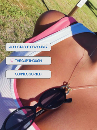 Close-up outdoor shot of a person's bare midsection wearing a pink, white, and blue striped sports bra, with a pair of black sunglasses resting on the chest and text overlays reading 'ADJUSTABLE, OBVIOUSLY', 'THE CLIP THOUGH', and 'SUNNIES SORTED'.