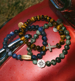 Three beaded bracelets with charms on a red surface