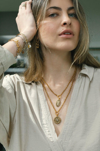 Woman wearing gold jewelry including necklaces and bracelets.